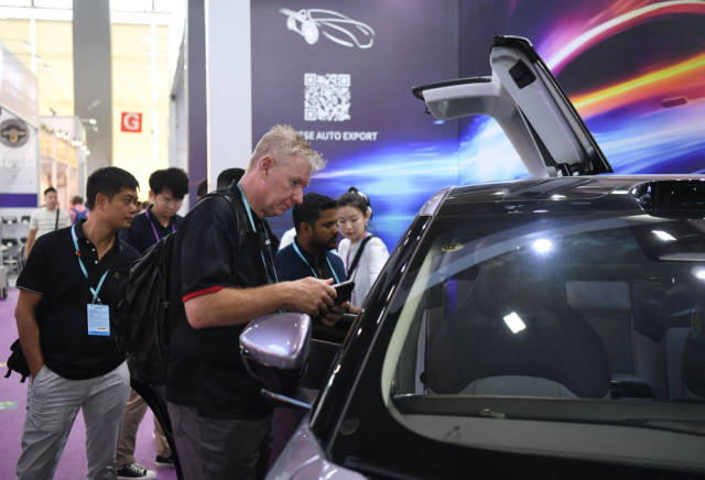 2023年10月16日，外国采购商观看广交会中国新能源汽车展台。新华社记者 邓华 摄